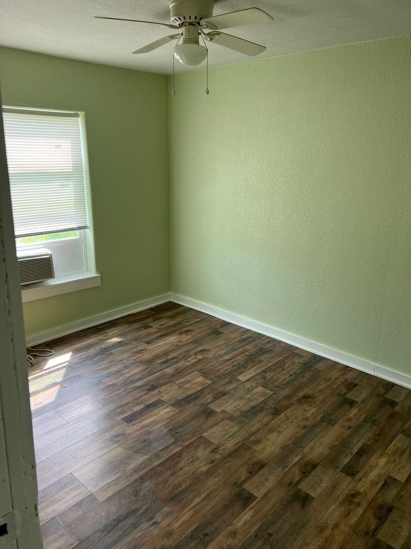 527 West 8th Street Freeport, TX 77541 - Photo 5 of 10 an empty room with wooden floor fan and windows