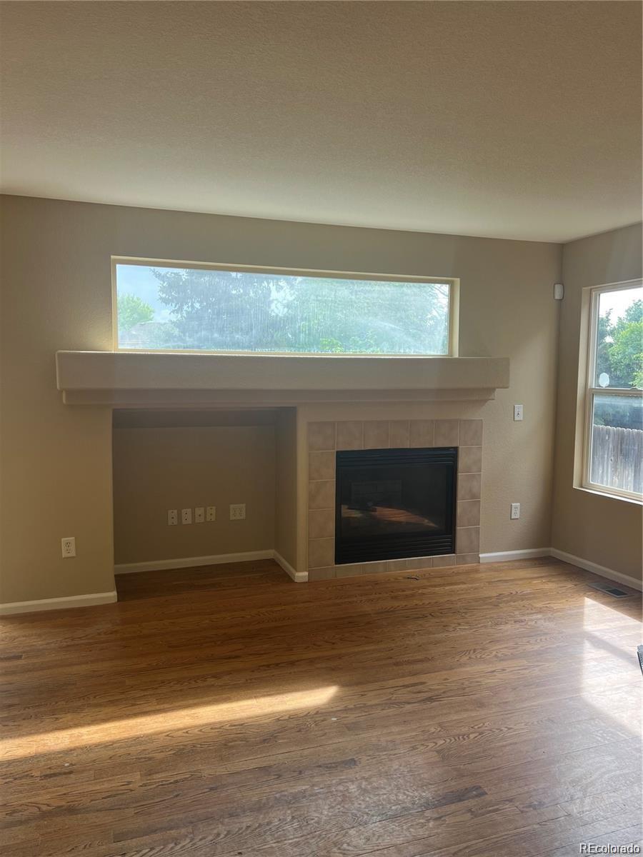 5353 Rhyolite Way Parker, CO 80134 - Photo 6 of 22 a view of empty room with wooden floor and fireplace