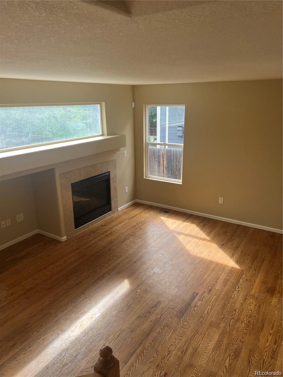 5353 Rhyolite Way Parker, CO 80134 - Photo 9 of 22 a view of empty room with wooden floor and fireplace