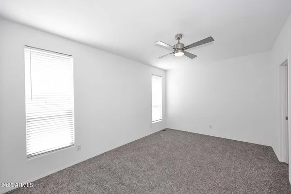 an empty room with windows and fan