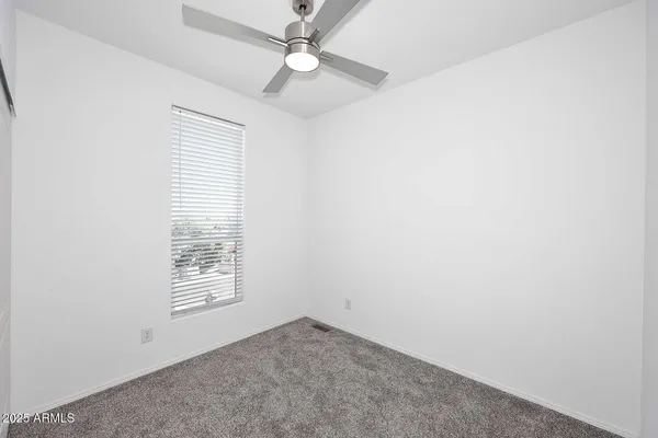 an empty room with windows and fan