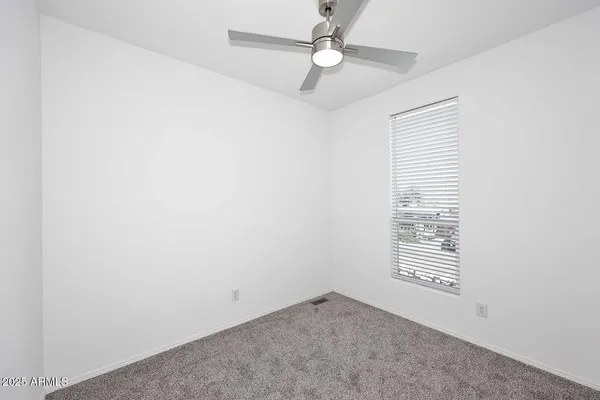 an empty room with a window and ceiling fan