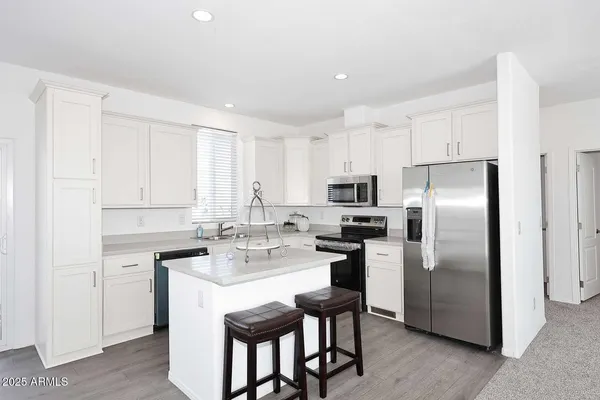 a kitchen with a refrigerator a sink dishwasher a stove and white cabinets with wooden floor