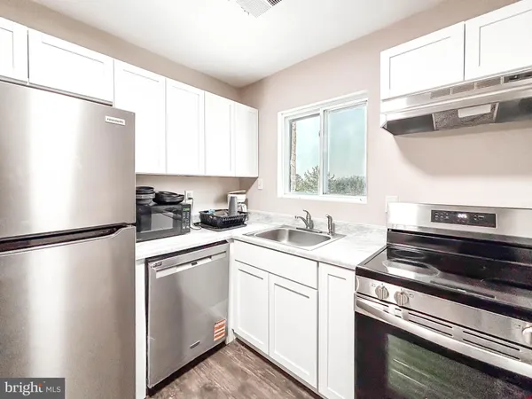 a view of a kitchen with a stove top oven a refrigerator with wooden floor