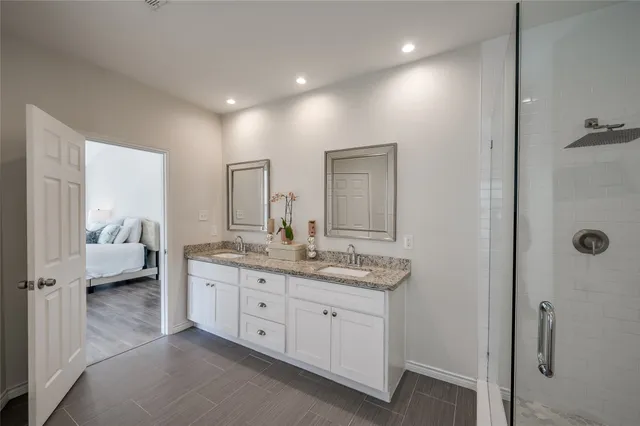 a en suite bathroom with a granite countertop sink and mirror