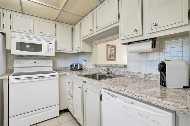 a kitchen with granite countertop white cabinets and white appliances