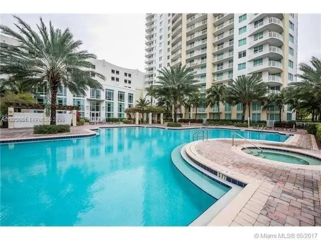 a view of a swimming pool with a lawn chairs and palm tree