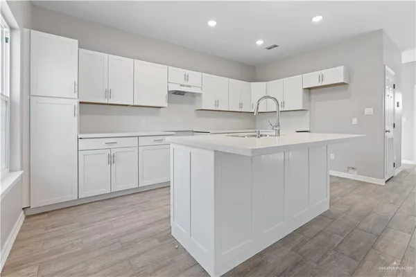 a kitchen with white cabinets appliances and sink
