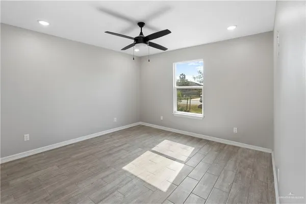 a view of empty room with wooden floor and fan