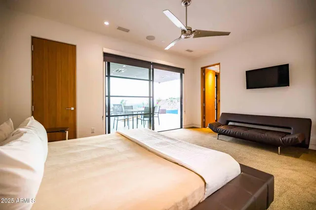 a bedroom with a bed a flat screen tv and a window