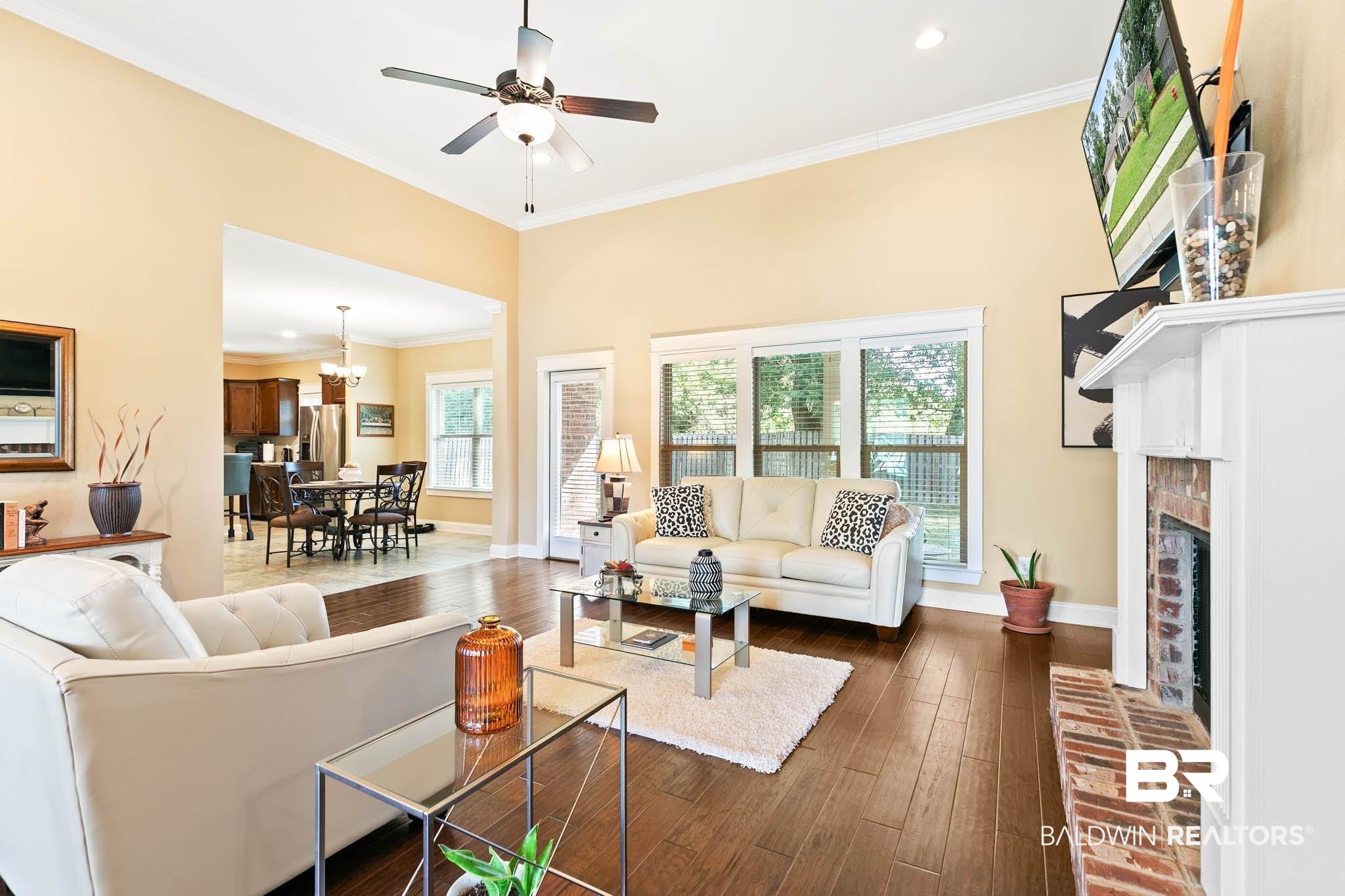 19740 Bunker Loop Fairhope, AL 36532 - Photo 4 of 33 Living area featuring crown molding, dark wood-style floors, a chandelier, ceiling fan, and a fireplace