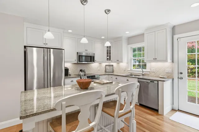 a kitchen with stainless steel appliances granite countertop a refrigerator a sink a stove a dining table and chairs