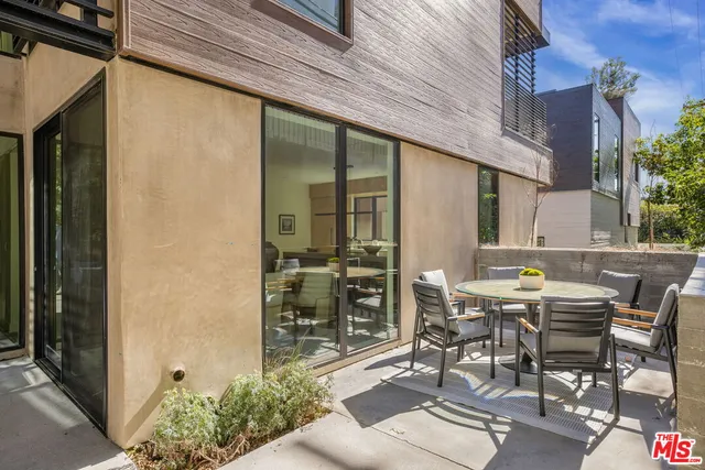 a patio with table and chairs and potted plants