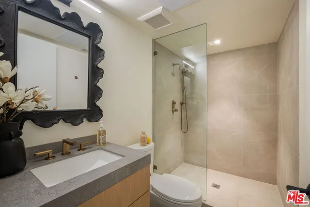 a bathroom with a granite countertop sink toilet a mirror and shower