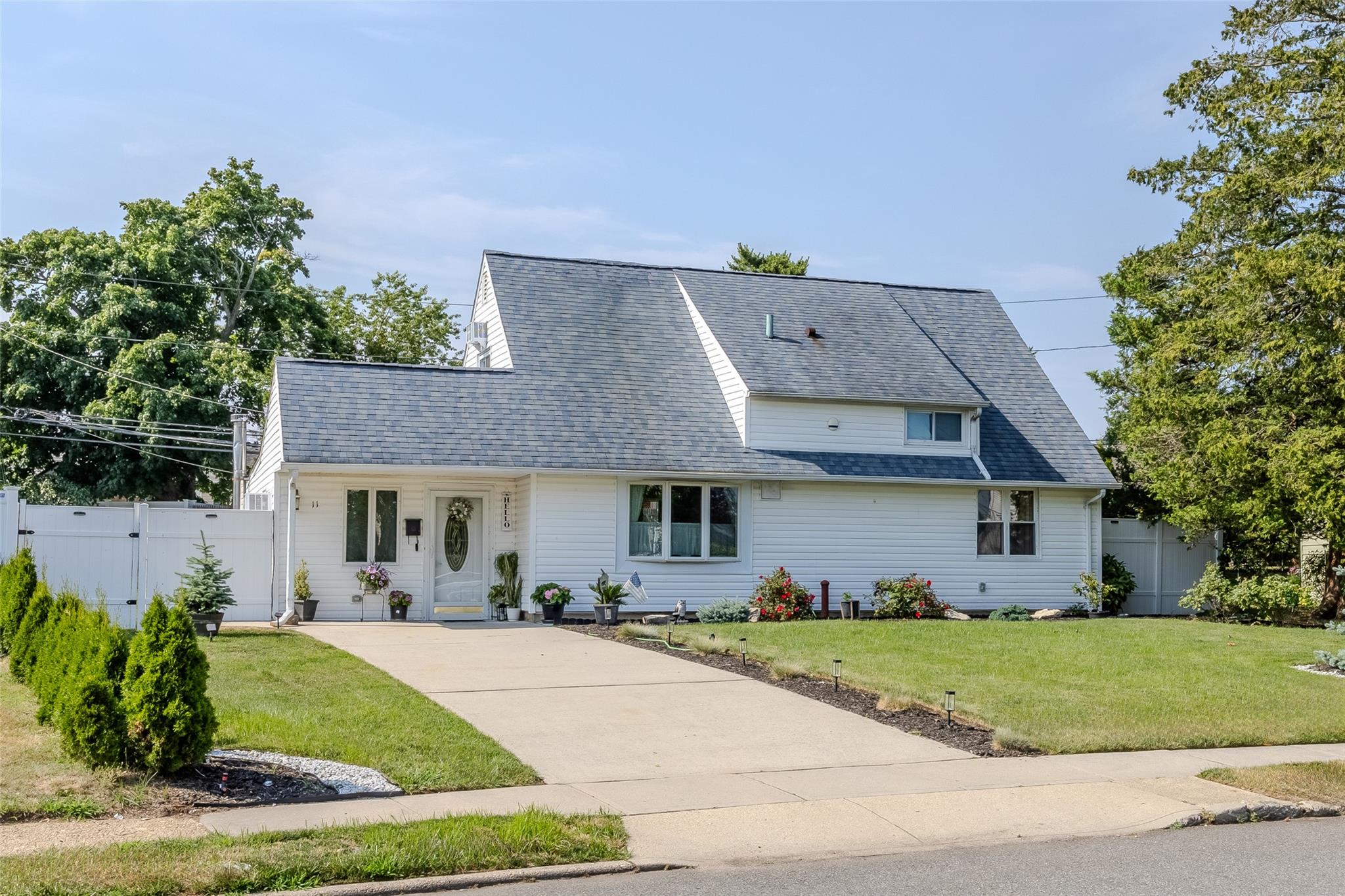 View of front of home featuring a front yard, a gate, fence, roof with shingles, and concrete driveway
