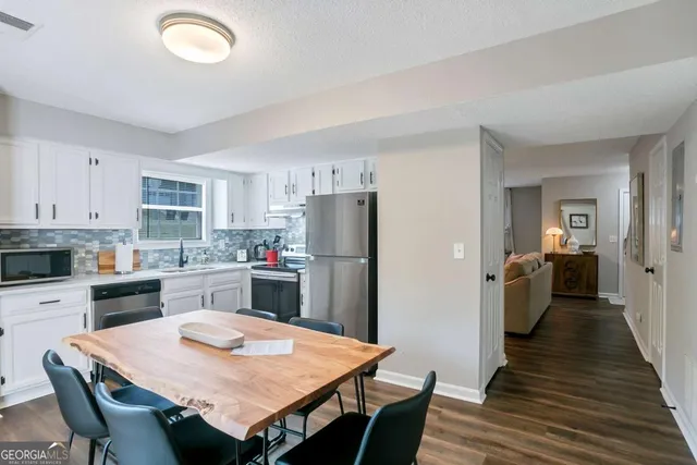 a kitchen with stainless steel appliances granite countertop a dining table chairs and refrigerator