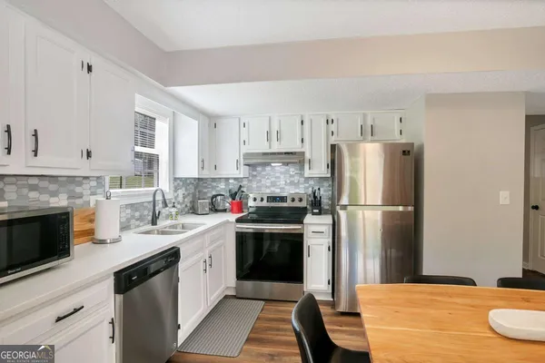 a kitchen with a sink a refrigerator and a stove top oven