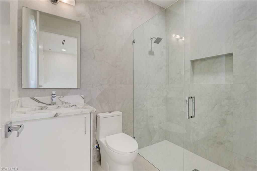 1150 8th Terrace North Naples, FL 34102 - Photo 28 of 39 Bathroom featuring vanity, tile walls, and a marble finish shower