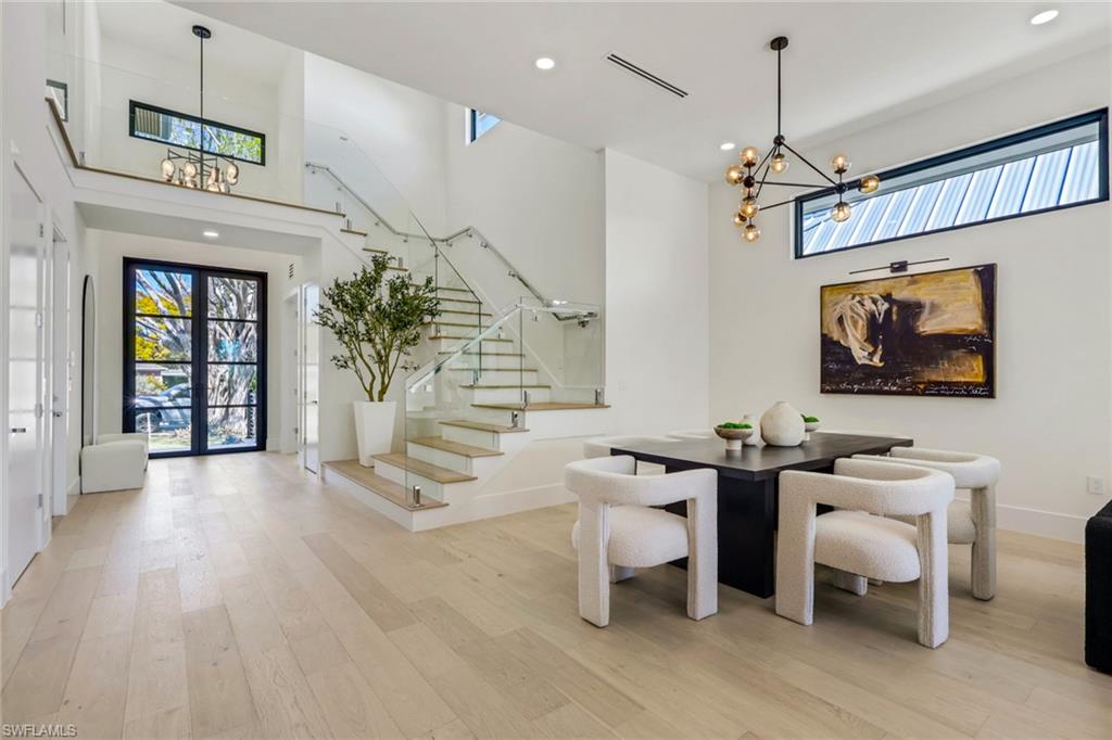 1150 8th Terrace North Naples, FL 34102 - Photo 6 of 39 Dining room featuring suspended lighting, a high ceiling, light wood-style floors, and plenty of natural light