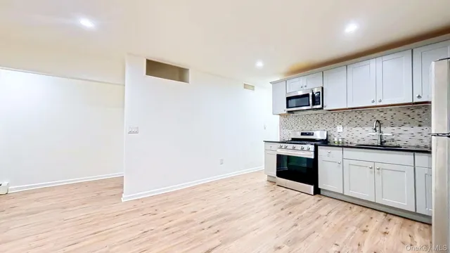 a kitchen with granite countertop a stove cabinets and wooden floor