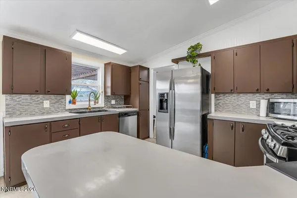 a kitchen with stainless steel appliances granite countertop a stove top oven a sink dishwasher a dining table and chairs with wooden floor