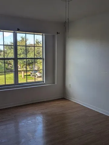 a view of an empty room with wooden floor and a window