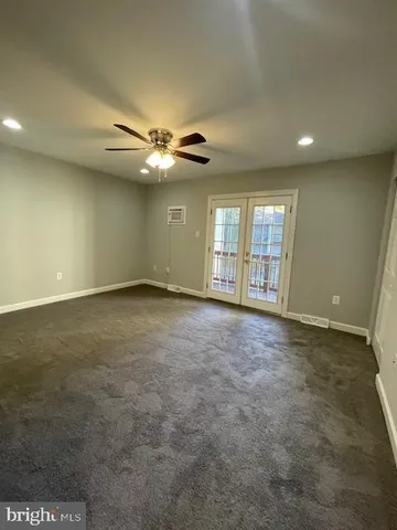 an empty room with chandelier fan and windows