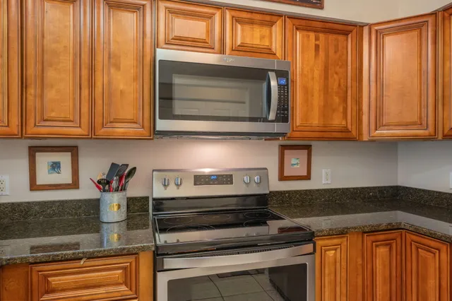 a kitchen with stainless steel appliances granite countertop white cabinets and a stove top oven