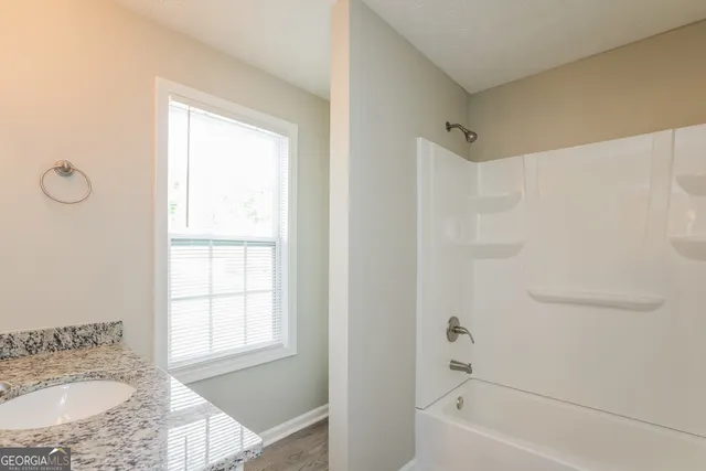 a bathroom with a granite countertop sink a window and a shower