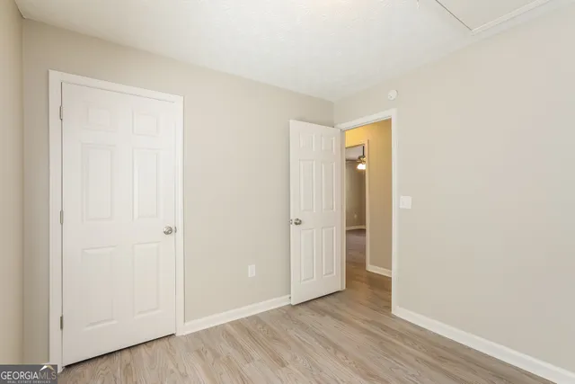 a view of an empty room with wooden floor and closet