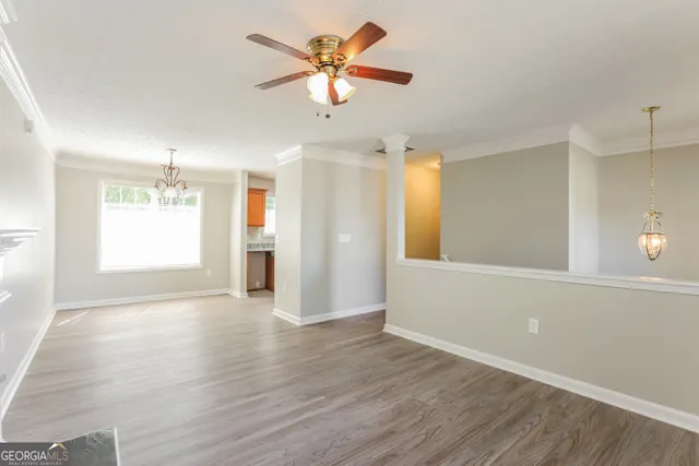 a view of an empty room with window and wooden floor