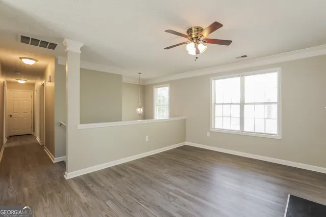 a view of an empty room with wooden floor and a window