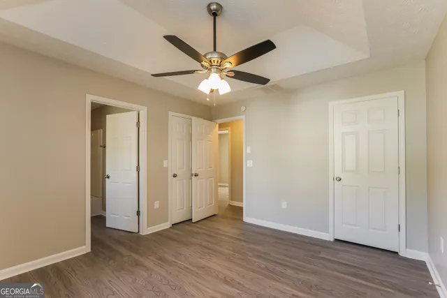 a view of an empty room with window a ceiling fan and wooden floor