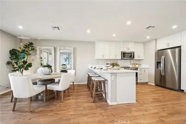 a kitchen with stainless steel appliances kitchen island granite countertop a table chairs and a refrigerator