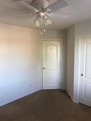 an empty room with closet and a chandelier fan