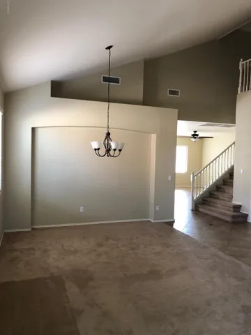 a view of an empty room with a chandelier fan
