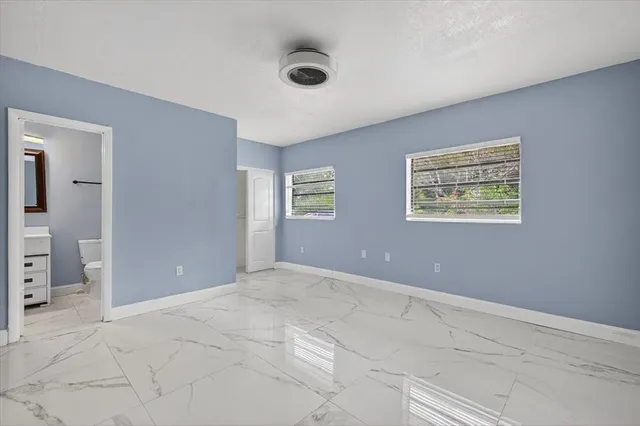 a view of an empty room with closet and a bathroom