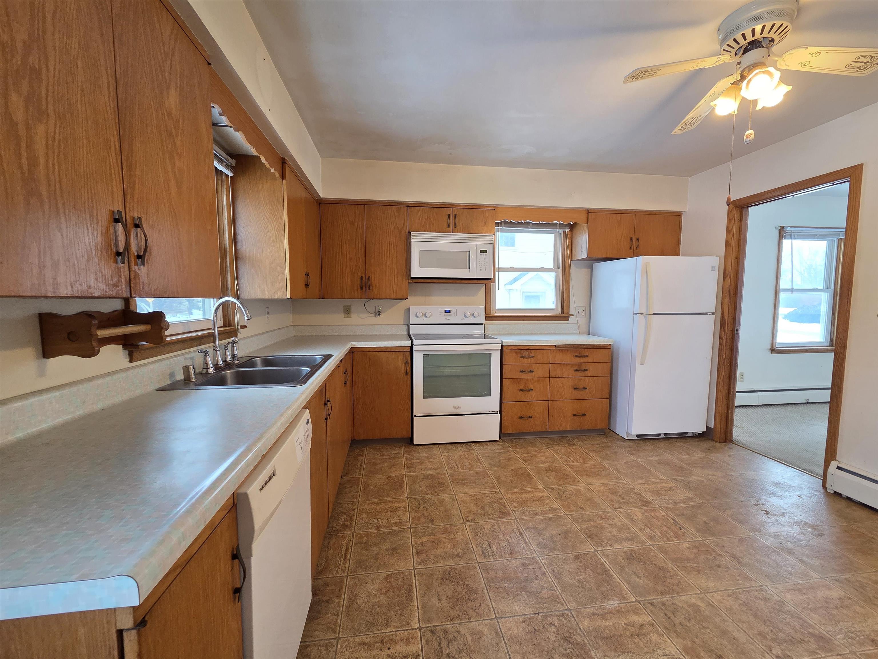 207 East 3rd Street Superior, WI 54880 - Photo 11 of 22 Kitchen with white appliances, plenty of natural light, light countertops, and brown cabinetry