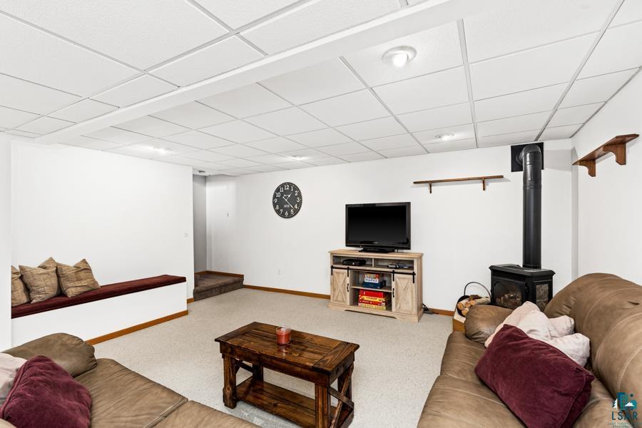 2020 East 11th Street Superior, WI 54880 - Photo 21 of 30 Living area featuring a drop ceiling, light carpet, and a wood stove