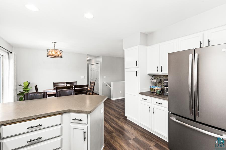 2020 East 11th Street Superior, WI 54880 - Photo 9 of 30 Kitchen with freestanding refrigerator, white cabinetry, dark wood finished floors, hanging light fixtures, and decorative backsplash