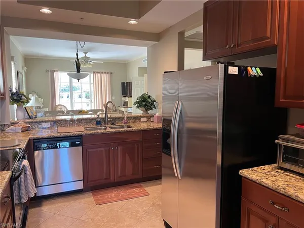 a kitchen with stainless steel appliances granite countertop a refrigerator a sink dishwasher and wooden cabinets with wooden floor