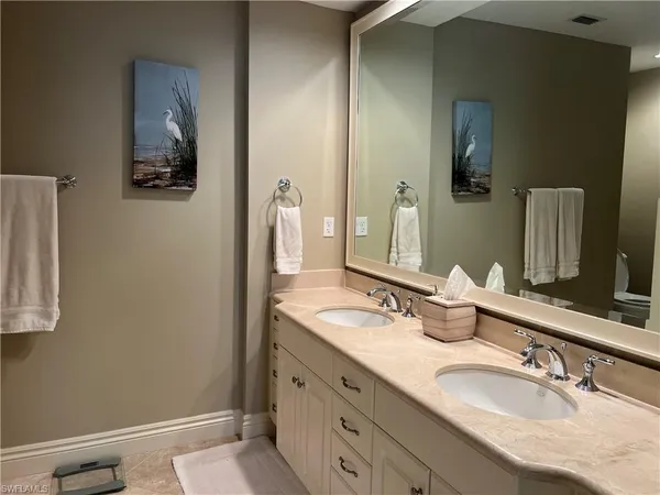 a bathroom with a granite countertop double vanity sink and a mirror