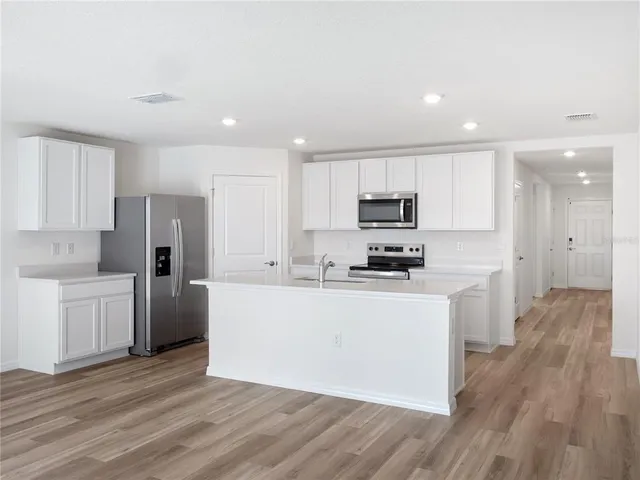 a kitchen with a refrigerator a stove top oven a sink and cabinets