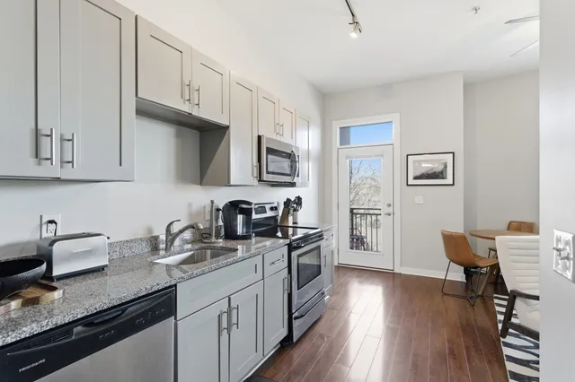a kitchen with granite countertop a sink dishwasher stove and wooden cabinets