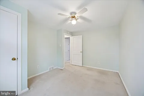 a view of an empty room with a chandelier fan
