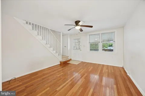 a view of empty room with wooden floor and fan