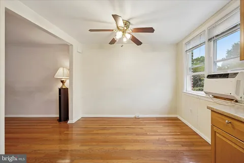 a view of empty room with wooden floor and fan