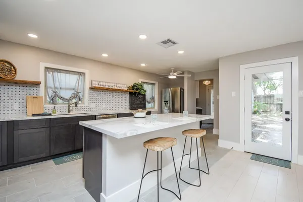 a kitchen with stainless steel appliances granite countertop table chairs sink and cabinets