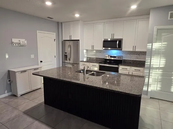a kitchen with stainless steel appliances granite countertop a stove a sink and a refrigerator
