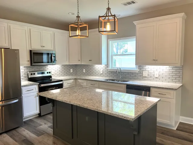 a kitchen with stainless steel appliances granite countertop a sink a stove and a refrigerator